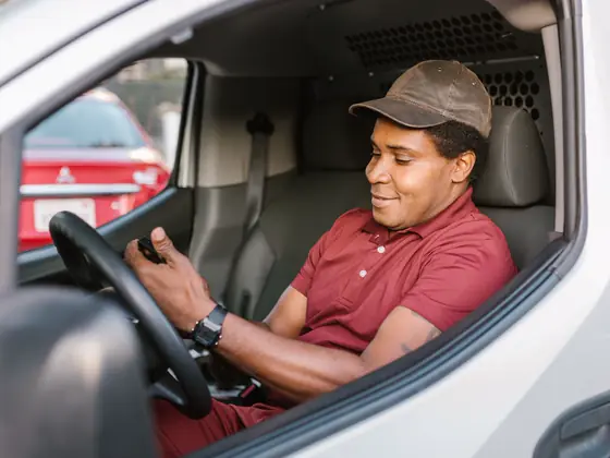 A tradesman in his work van checking his phone.
