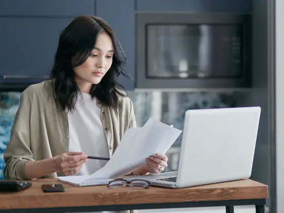 A woman at a table comparing a printed quote with her laptop.