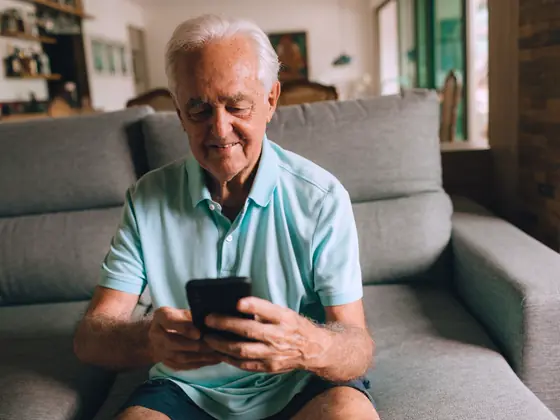 A man at home on his sofa, looking at his phone.
