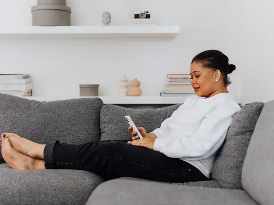 A woman on her couch looking something up on her phone.