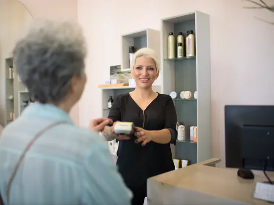 A salon owner at the front desk taking payment from a customer.