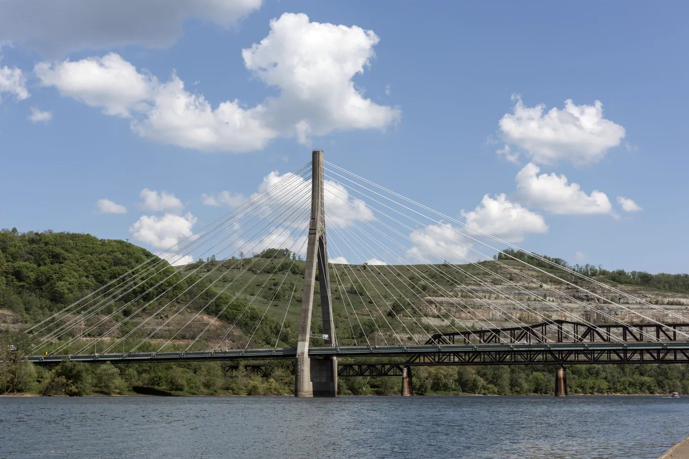 The Veterans Memorial Bridge at Steubenville, Ohio: one concrete tower and its cables over the Ohio River, green hills behind.