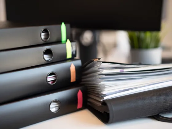 Tabbed binders full of documents on an office desk.
