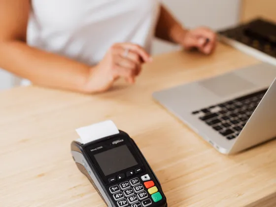 A card payment terminal beside a laptop on a shop counter.