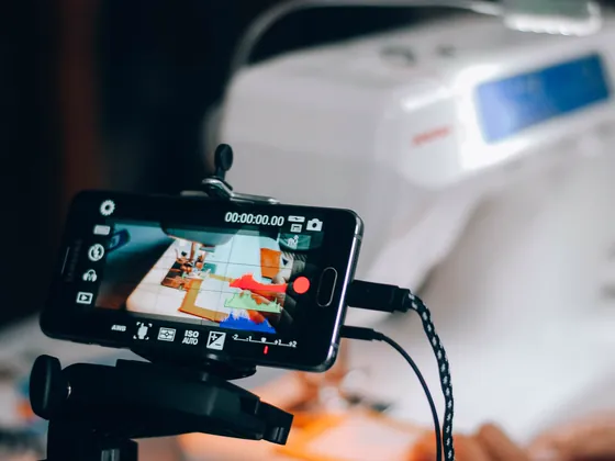 A phone on a small tripod recording a sewing machine at work.