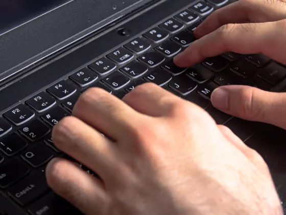 Two hands on a laptop keyboard.